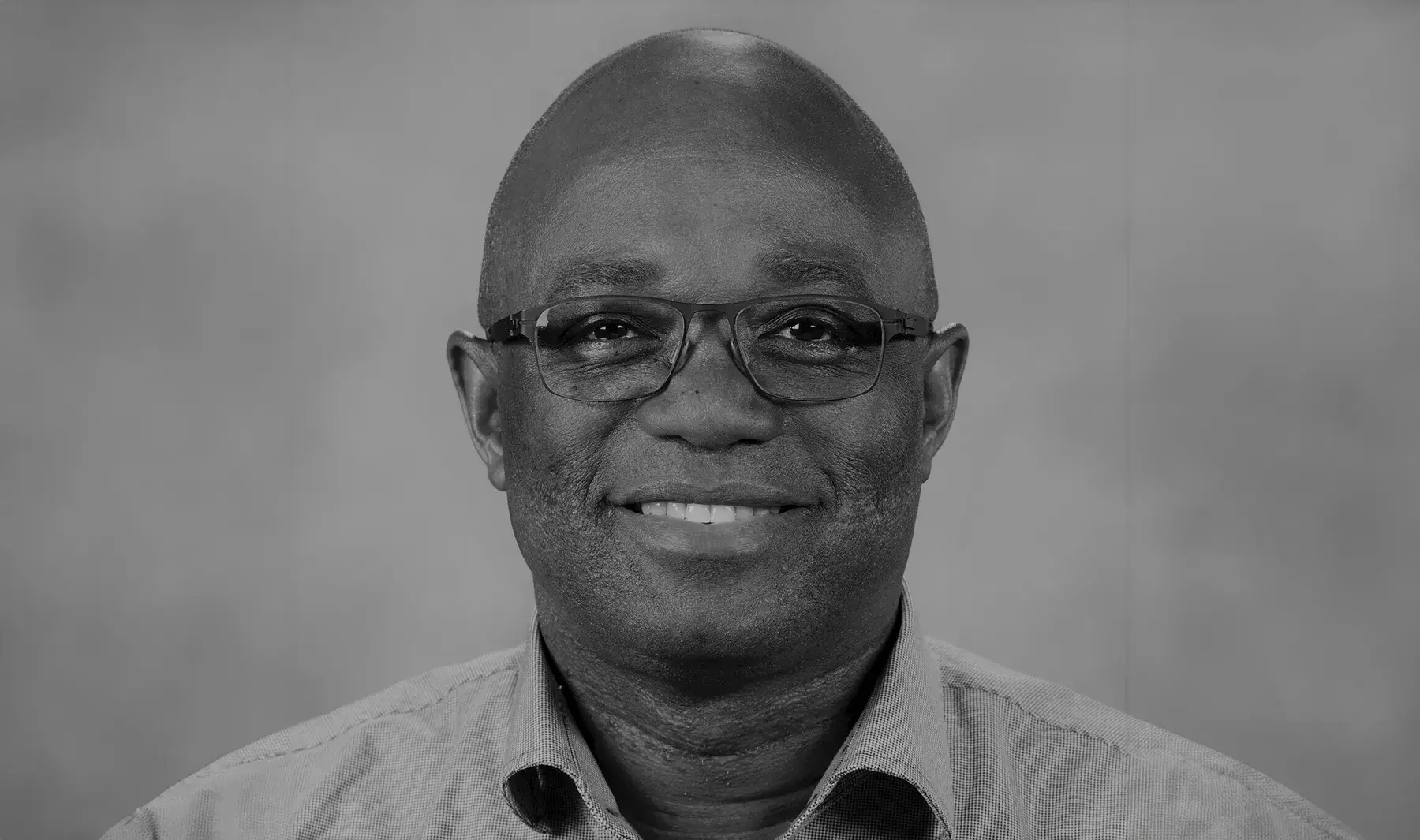 black and white portrait of Prosper Boyaka, PhD wearing glasses and smiling