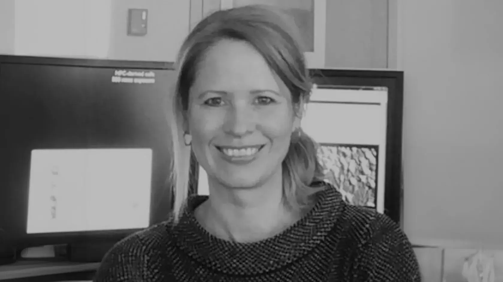black and white portrait of Kari Hoyt, PhD smiling in front of computer monitors