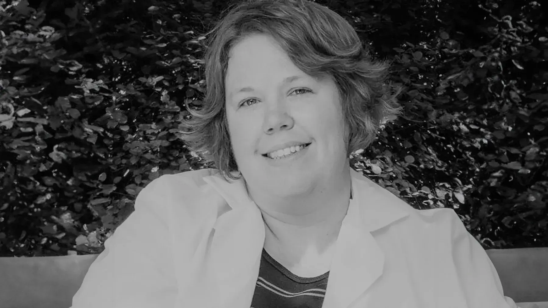 black and white portrait of Sarah Moore, DVM wearing a light colored jacket in an outdoor setting