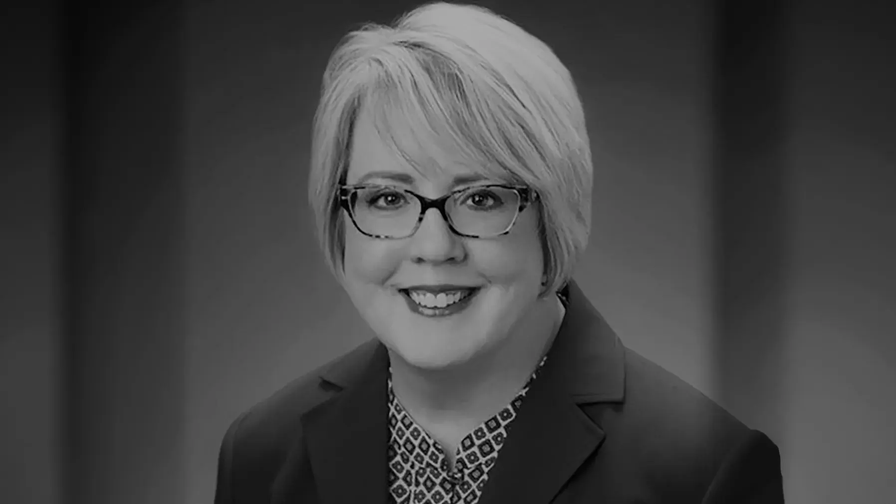 black and white portrait of Marcia Worley, PhD, RPh wearing a patterned shirt and dark suit coat 