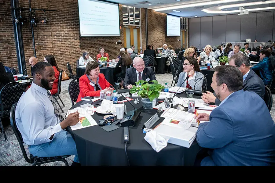 Many groups of people sitting around circular tables and talking