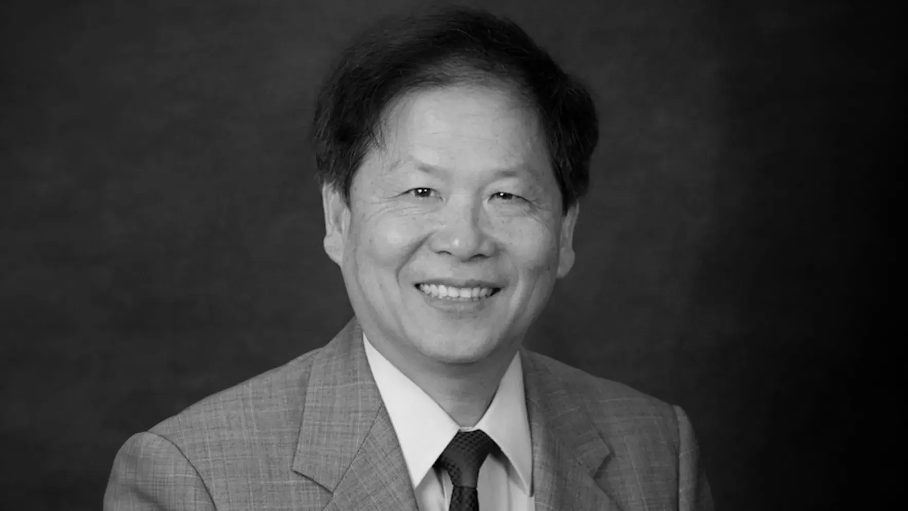 black and white portrait of Peixuan Guo, PhD smiling wearing a suit and tie