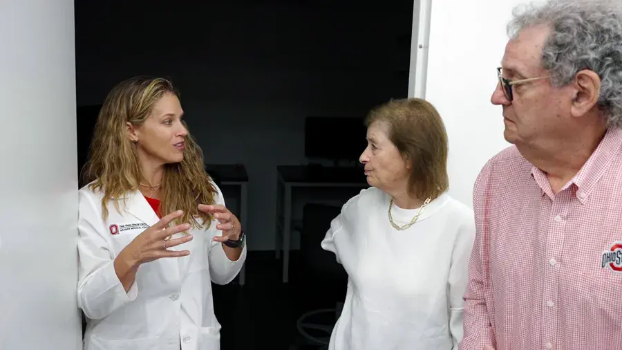 Two women and a man stand and talk