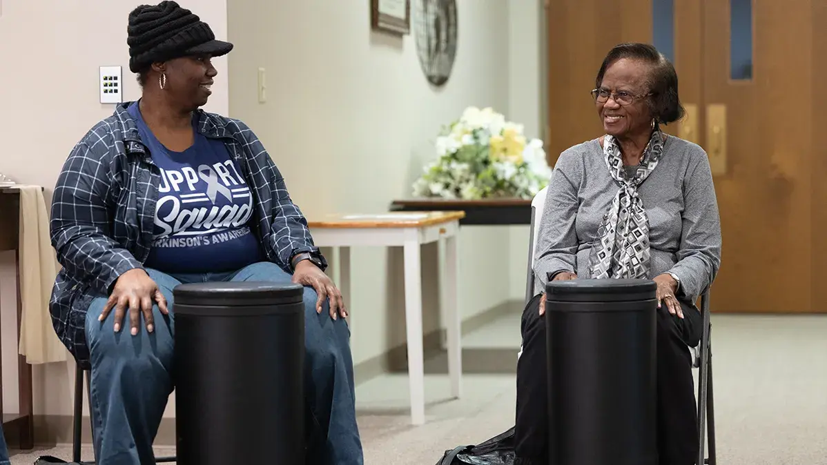 Two women are seated with drums in front of them.