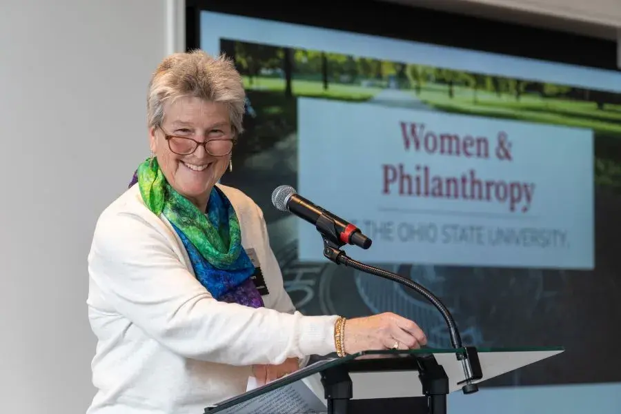 A woman stands at a podium and takes a moment to smile for the camera during her speech
