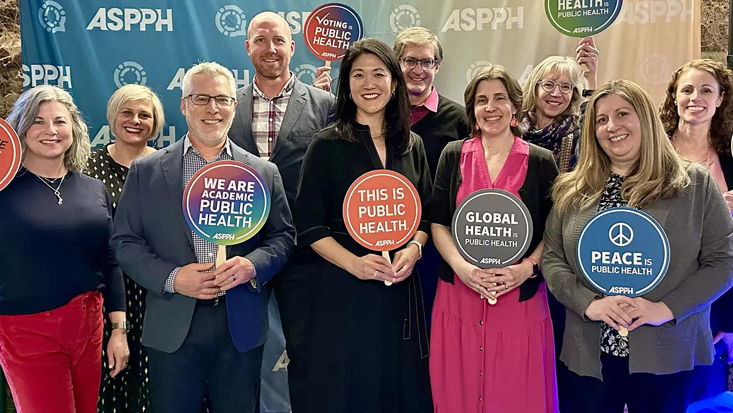 A group of people holding a variety of public health messaging signs pose for a picture.