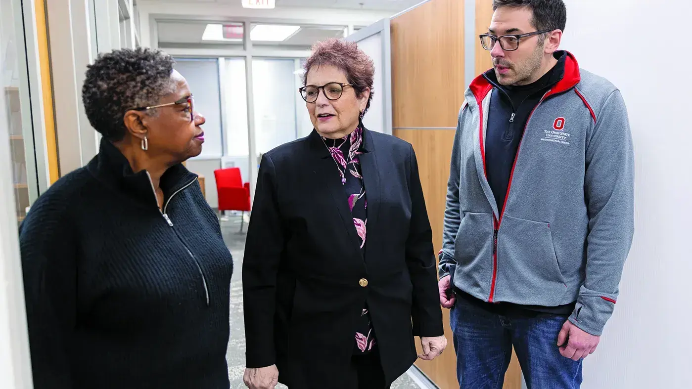 Electra Paskett, Ohio State researcher, talking with two other individuals in a hallway.