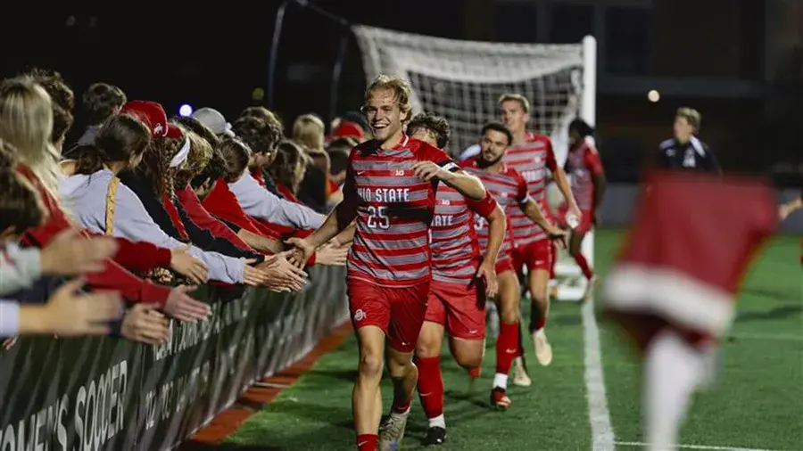 Ohio State men's soccer team running in a line and giving high-fives to the crowd.