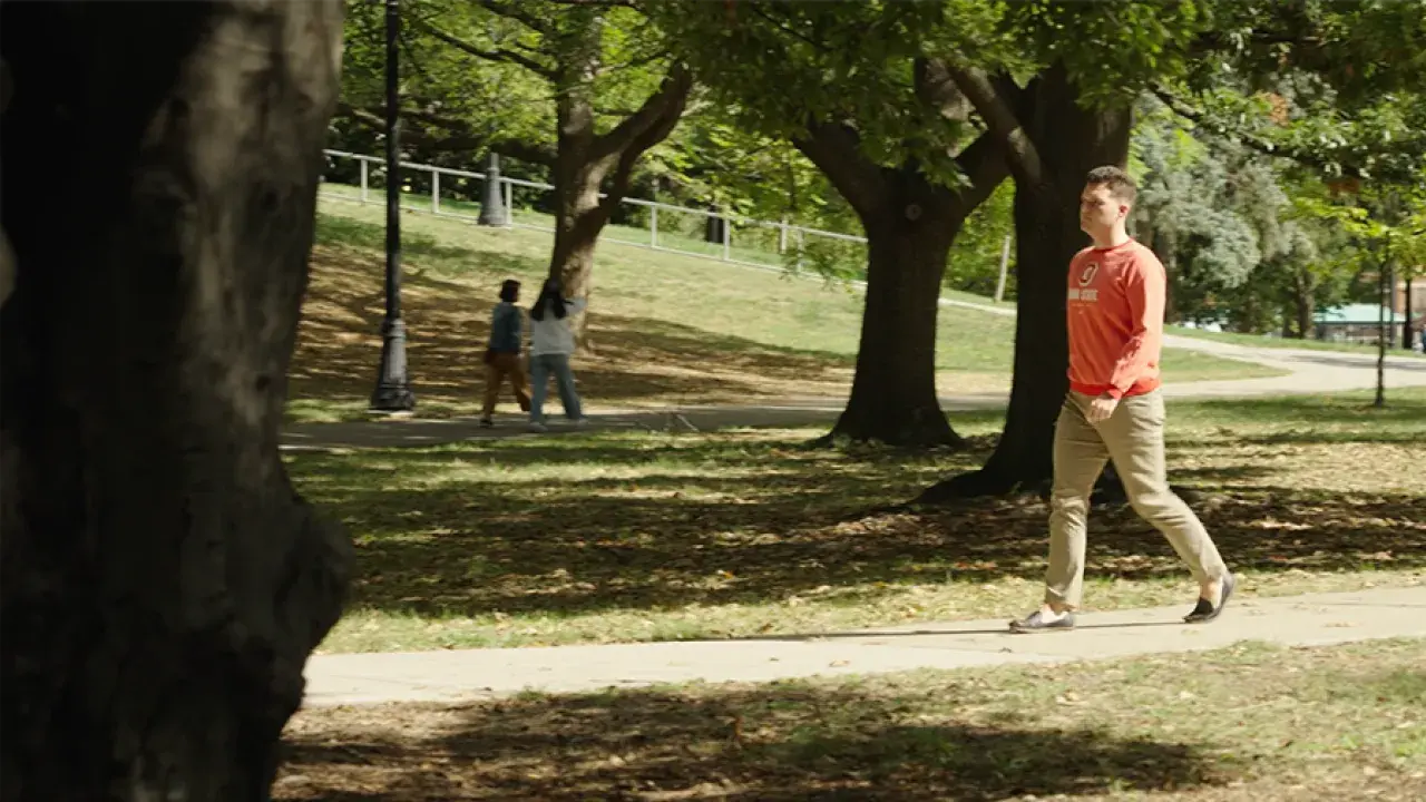 Dylan Page walking on across campus on a sunny day.