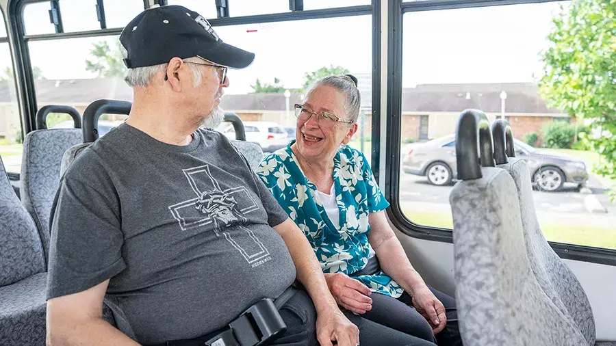 Two people sitting on a bus and talking.