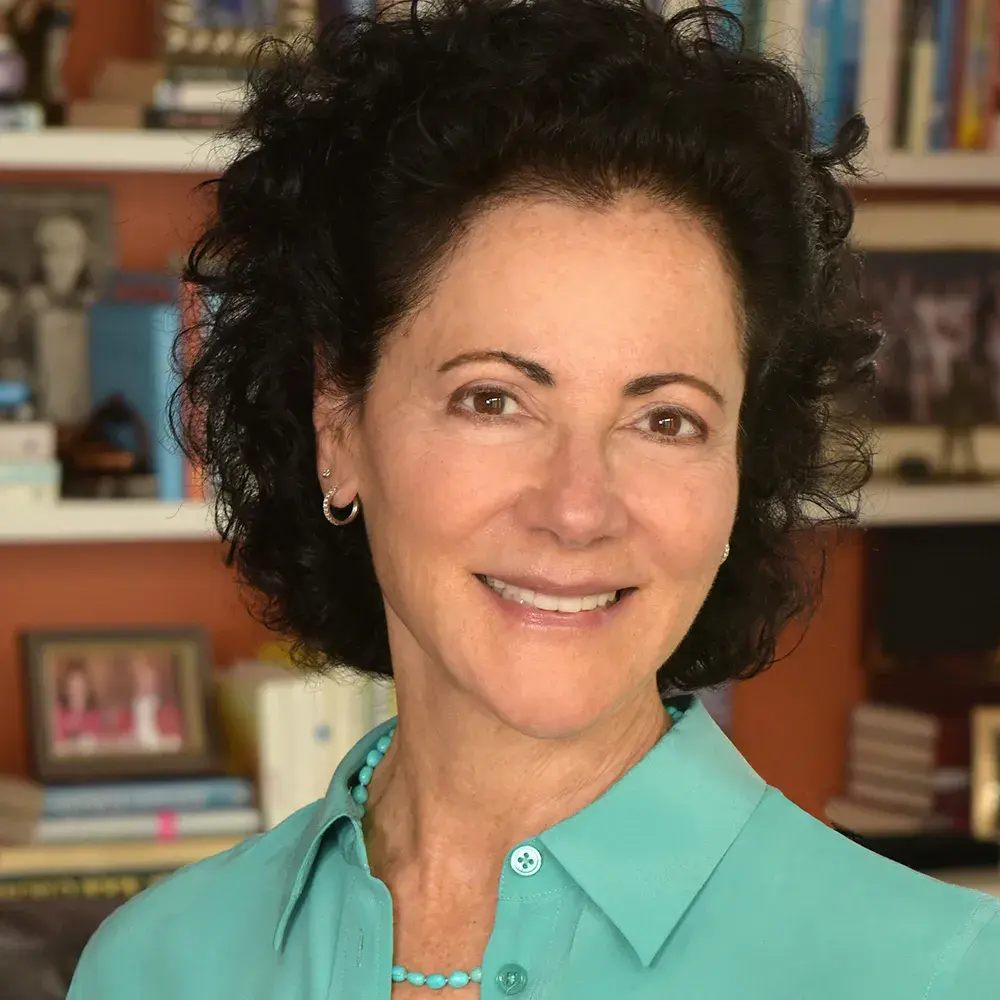 Linda Kass smiles and wears a light green shirt and matching necklace
