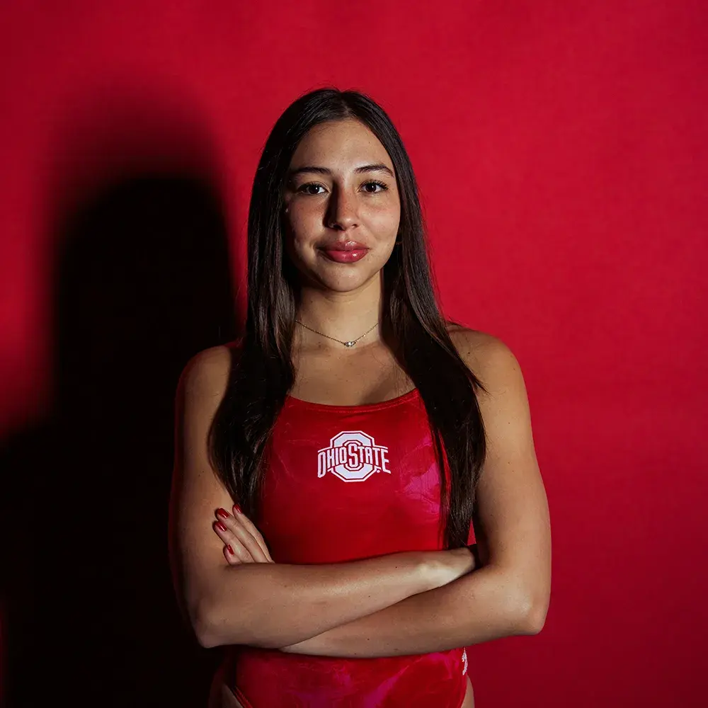 Daniella Arango Molano posing in a red Ohio State swimsuit with a red background.