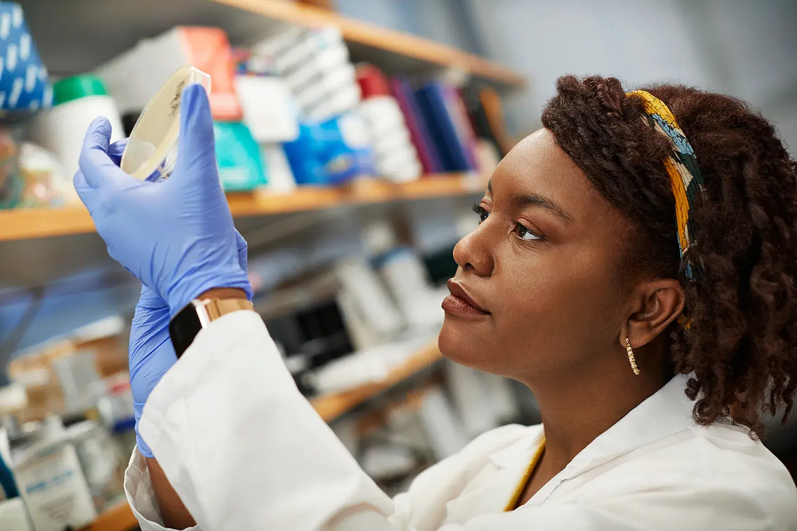 Female medical student in lab coat and gloves studying a sample