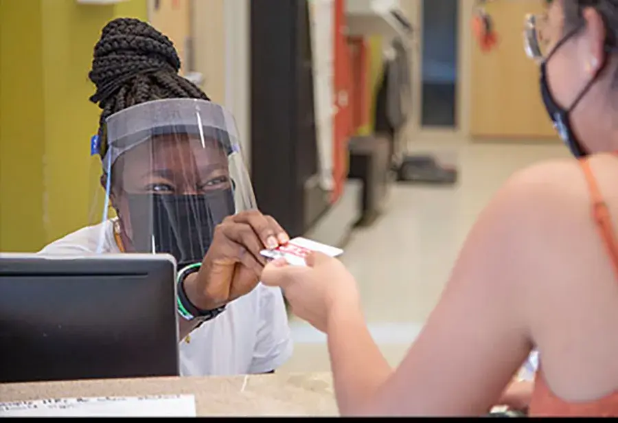Hospital worker wearing a mask and face shield handing a patient a card
