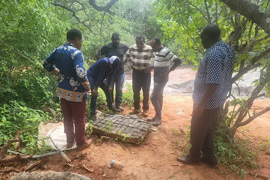 A group of men in Marwa Village stand at a water drilling site