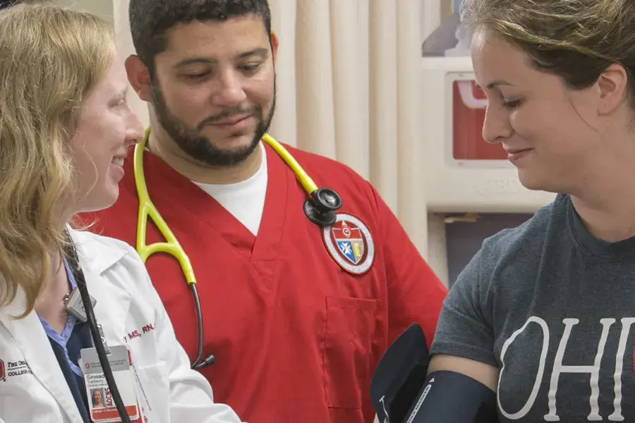 A female doctor and a male nursing student assist a patient