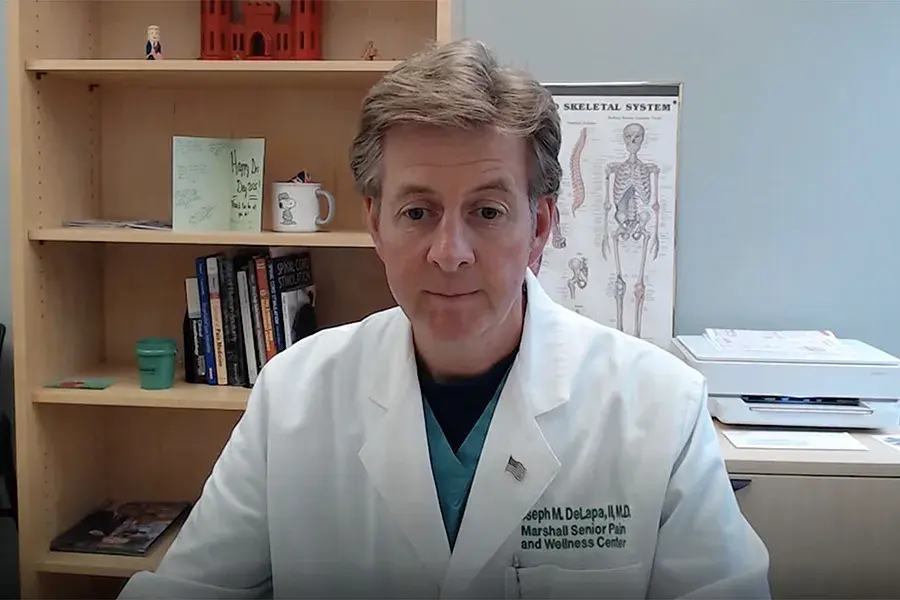 Dr. Joseph DeLapa sits at a desk in his office