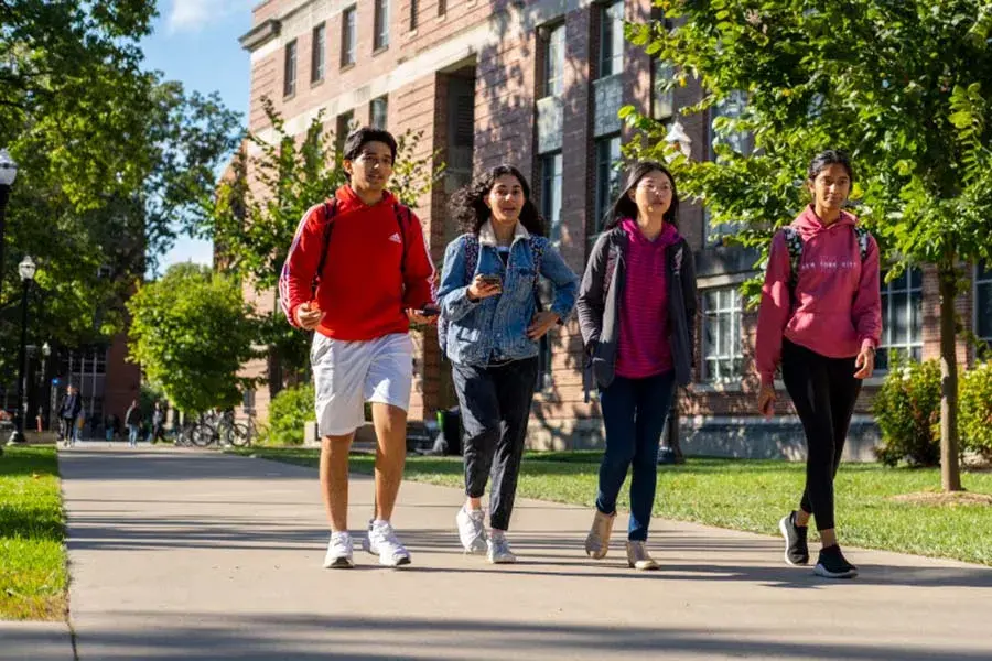 Four students walk outside on a campus sidewalk