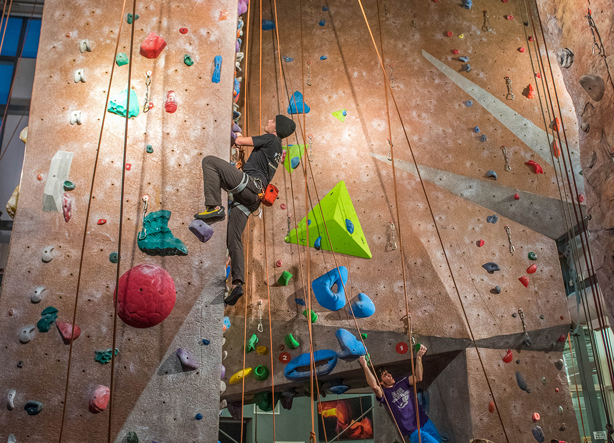 A student climbs up the climbing wall at the Outdoor Adventure Center.
