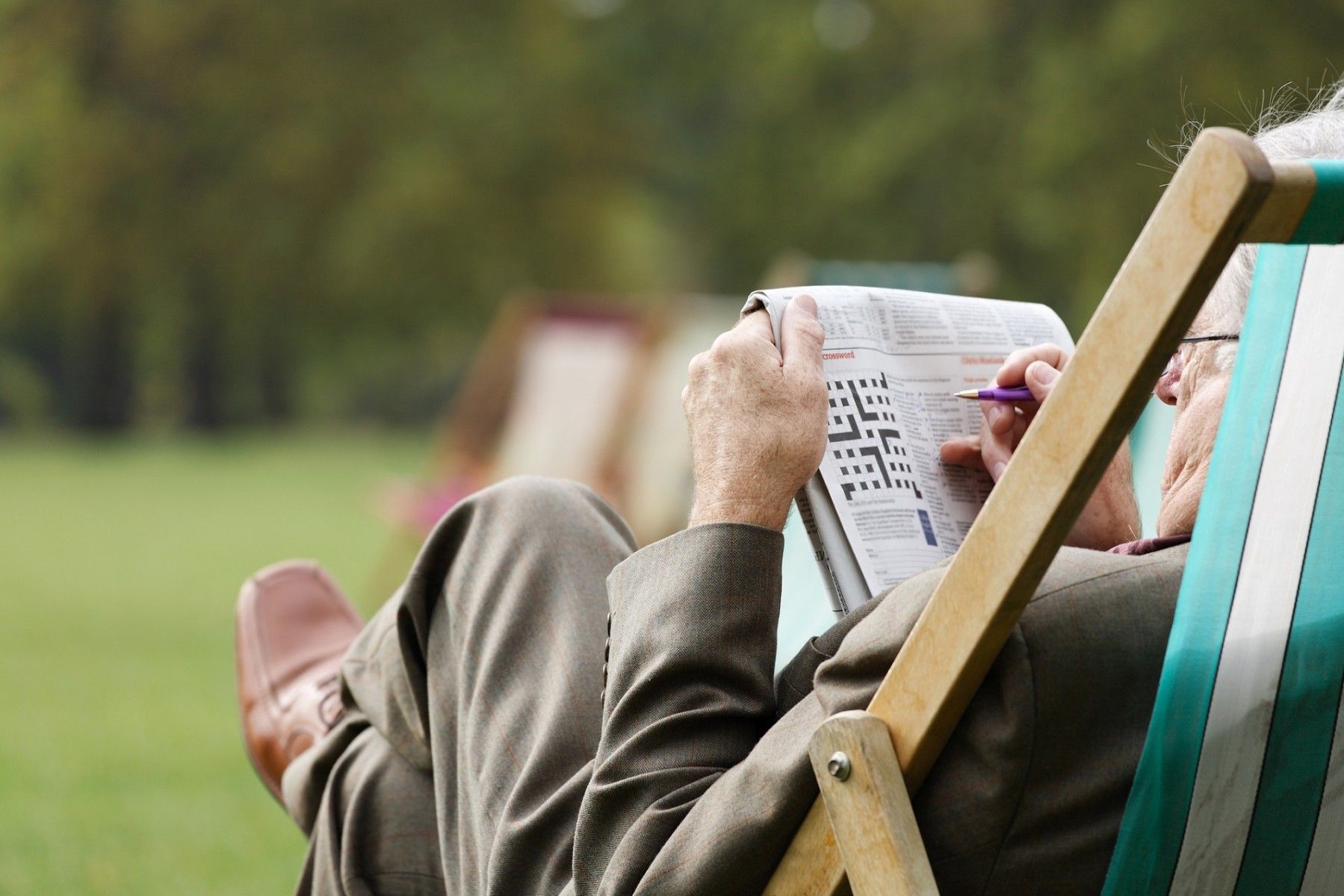 An elderly works on a crossword puzzle.