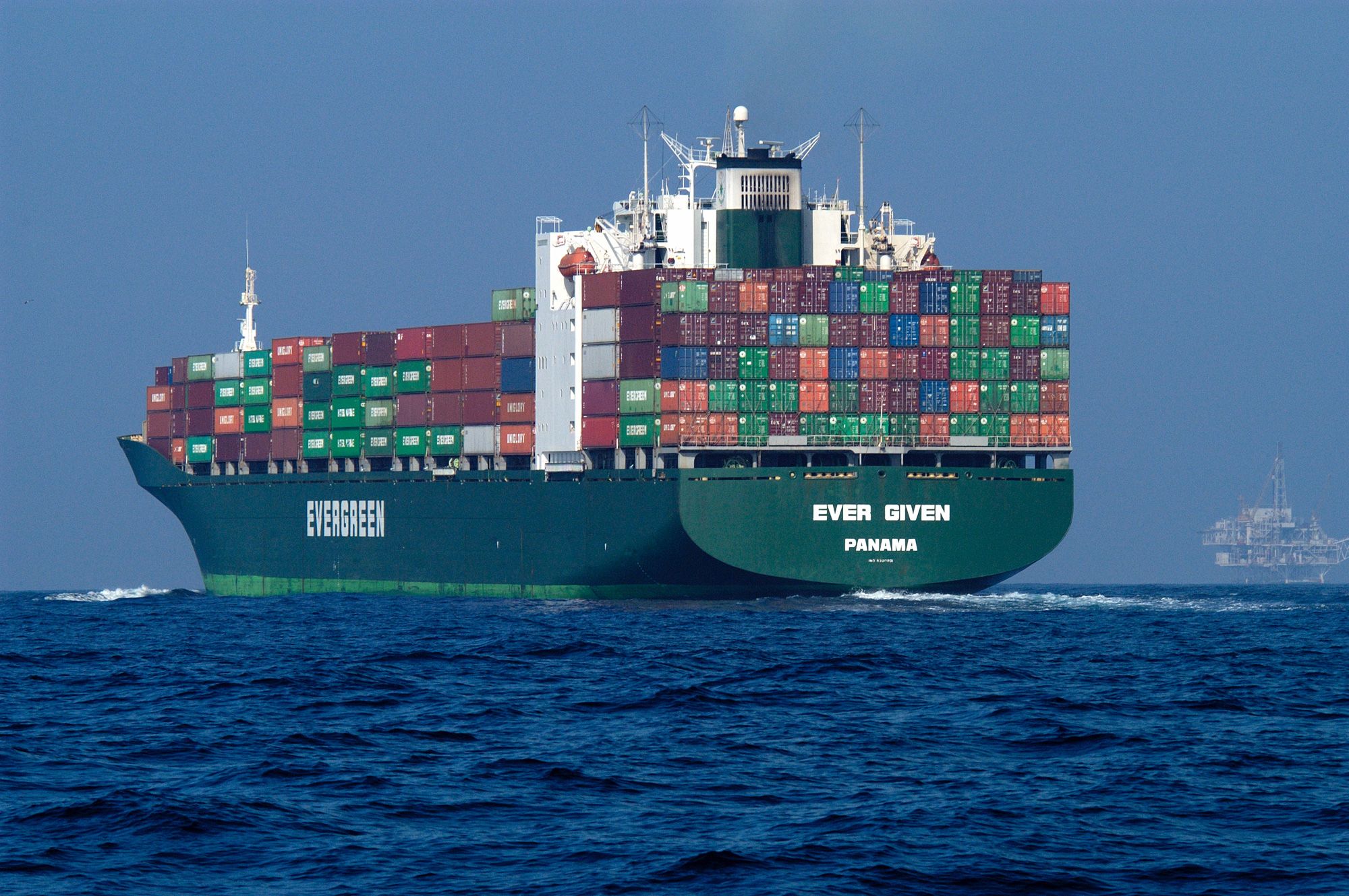 A ship with many containers makes its way across the water.