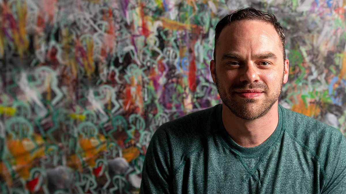 AJ Heckman in front of his paintings.