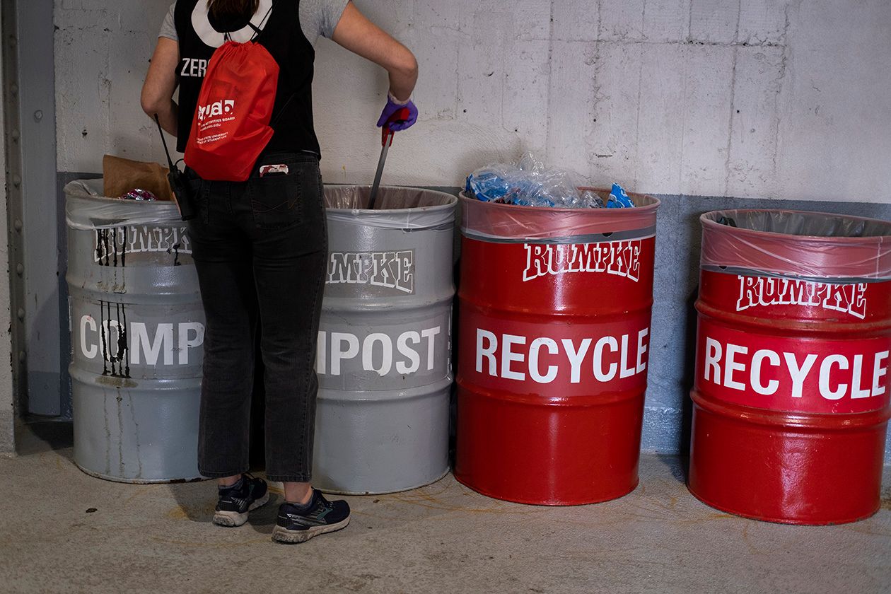 Student volunteer sorting trash into compost and recycling bins