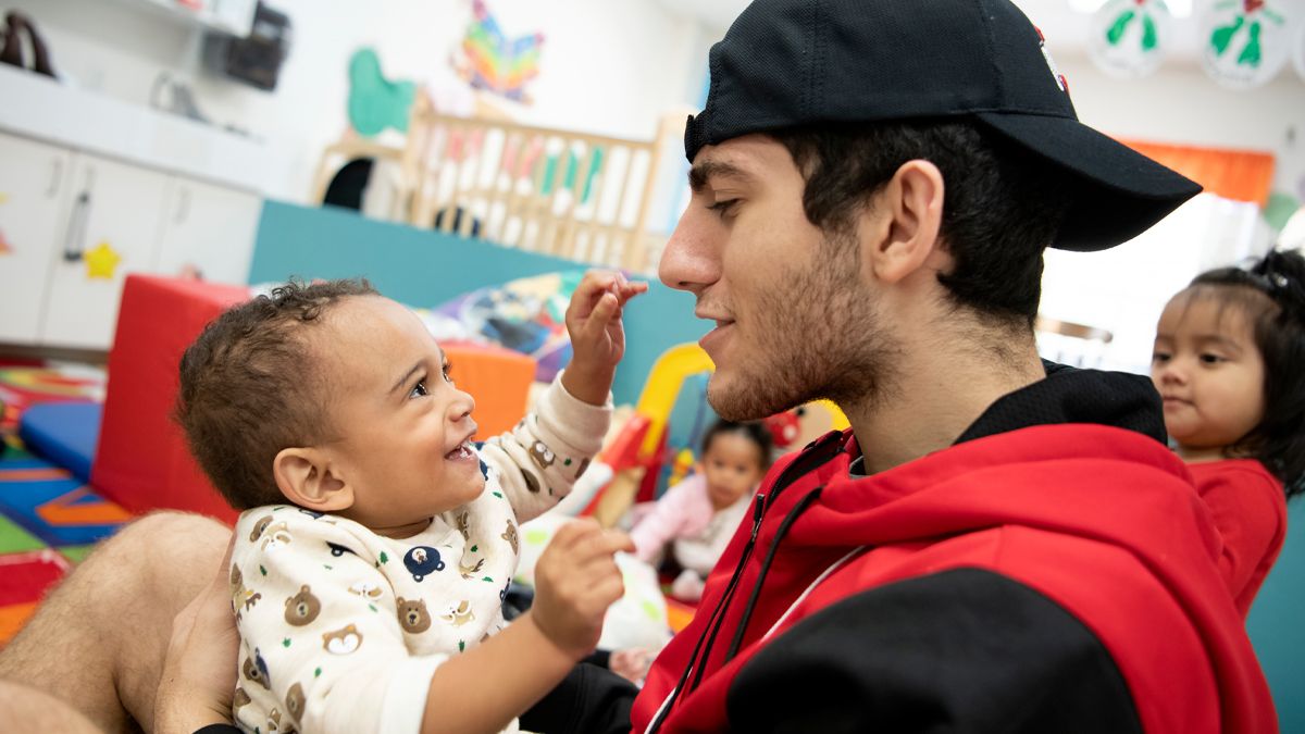 A Buck-I-SERV student holds a smiling infant