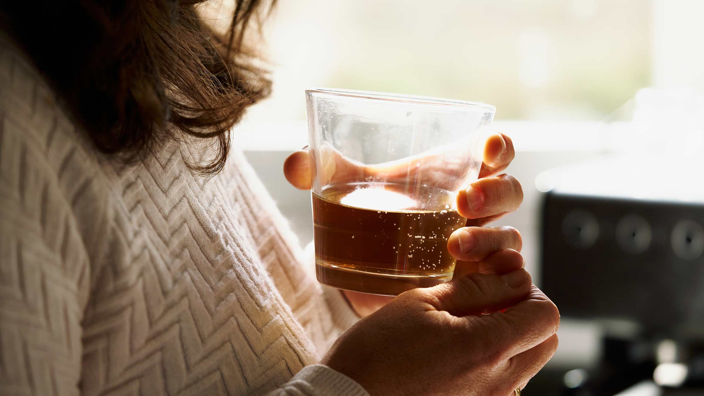 A woman holds a drink.