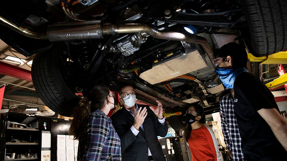Shawn Midlam-Mohler talking to students while a car is suspended overhead