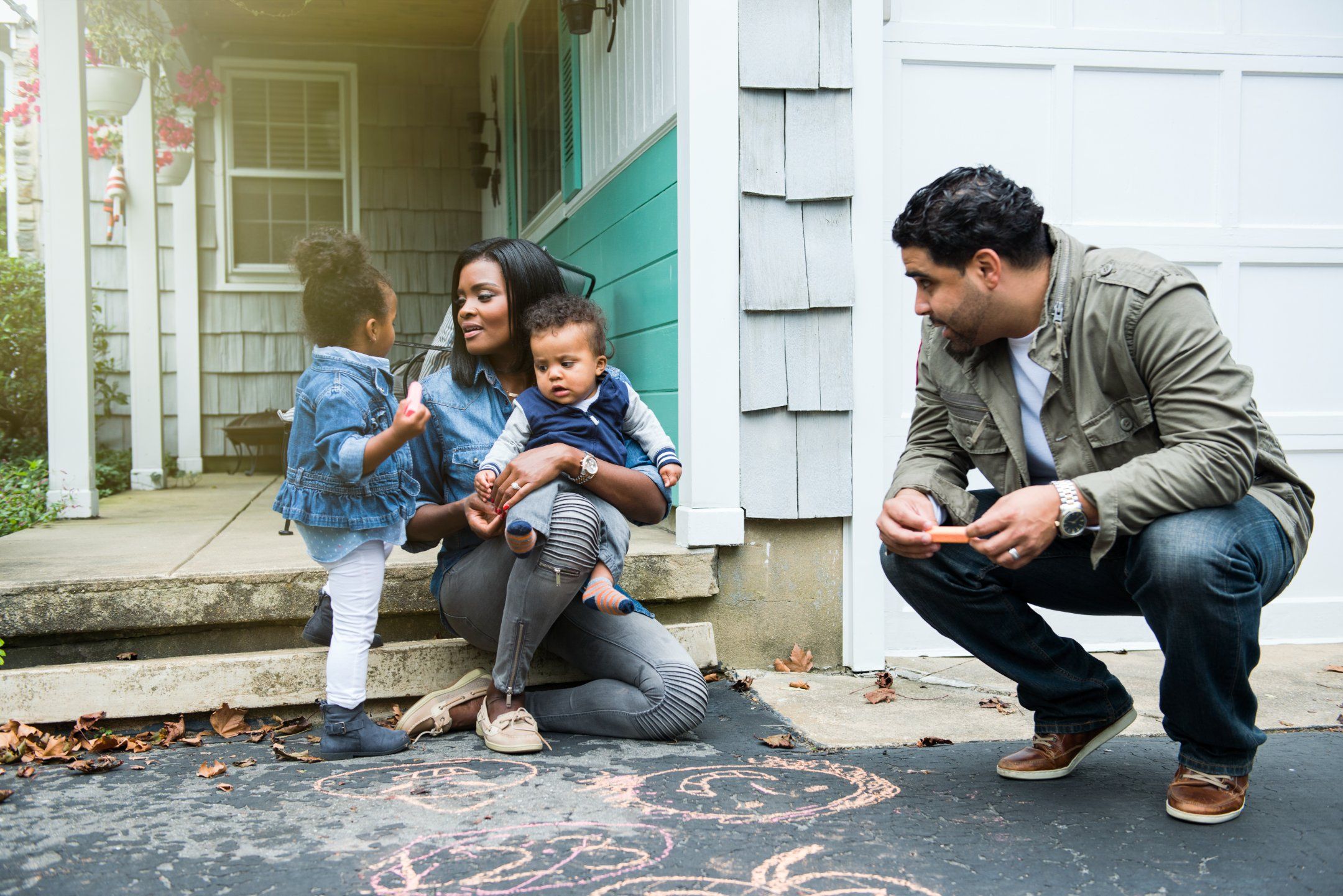 A woman with two young children while a man crouches next to her.