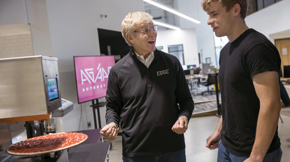 Jim Grote talks with Ohio State student Hayden Frea, who shares a patent on a pizza saucing machine with other interns