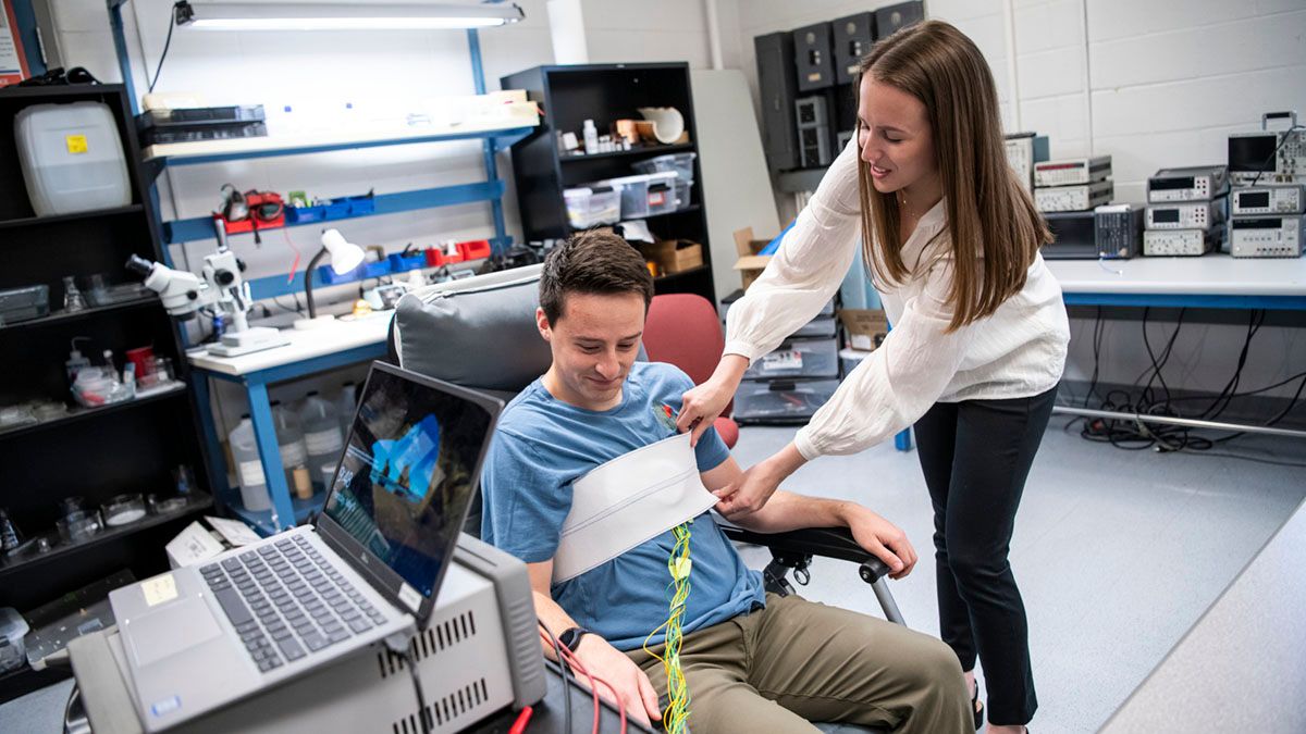 Rice adjusting wearable technology on a man sitting in a chair