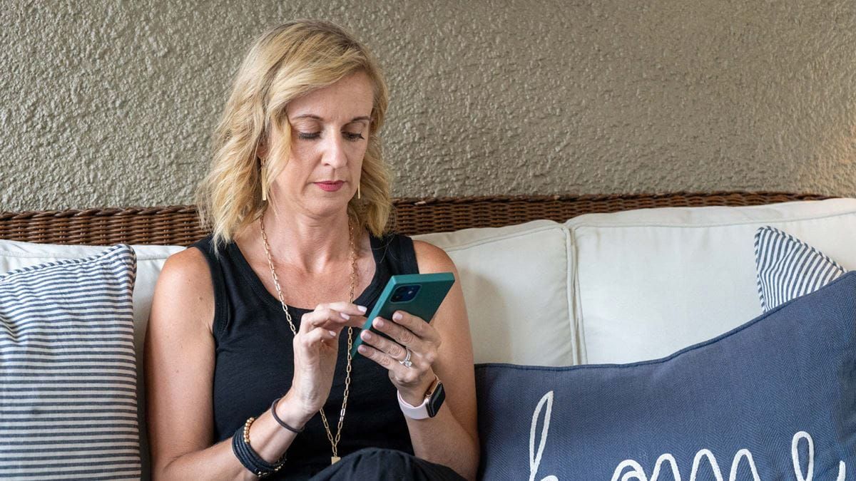 A woman scrolls on her phone while in bed.