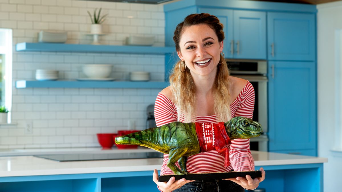 Natalie Sideserf poses with a dinosaur cake