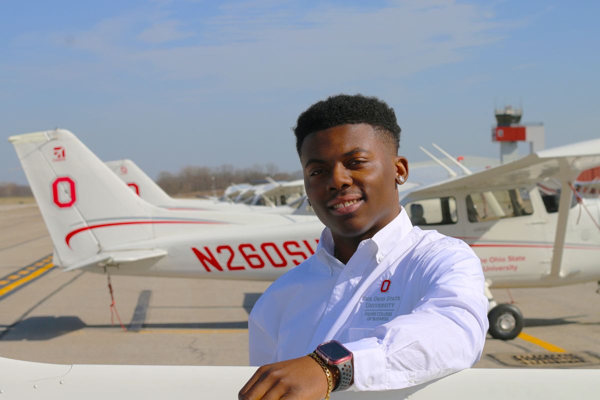 Ohio State student Torrington Ford stands in front of a plane.