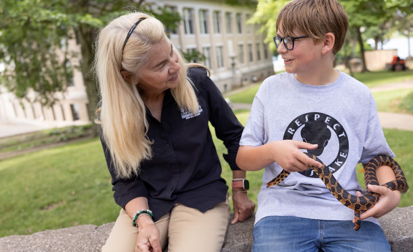 Susan Bixler talks with Spencer Knisely, who is holding a snake.