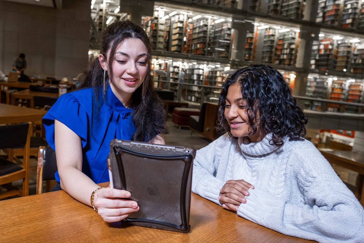 Pelorus Health founder Anjali Prabhakaran, right, huddles around a tablet with business partner Angelina Atieh, a third-year student, at Thompson Library.
