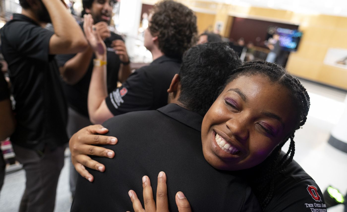 Two students smile and hug.