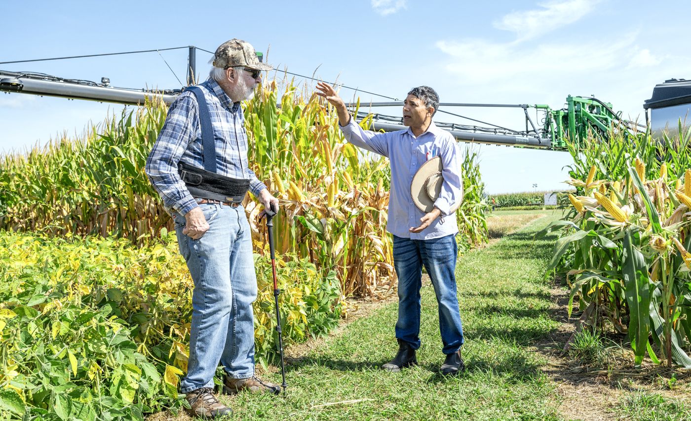 An Ohio farmer speaks with a researcher from Ohio State as both stand in a corn field