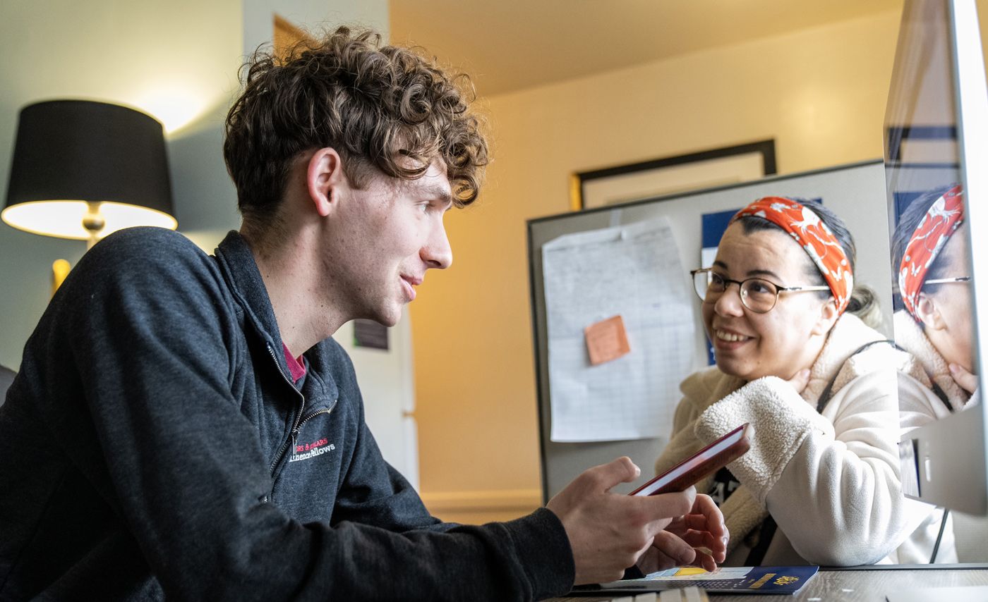 Larkin Cleland in discussion with a woman while at a computer.