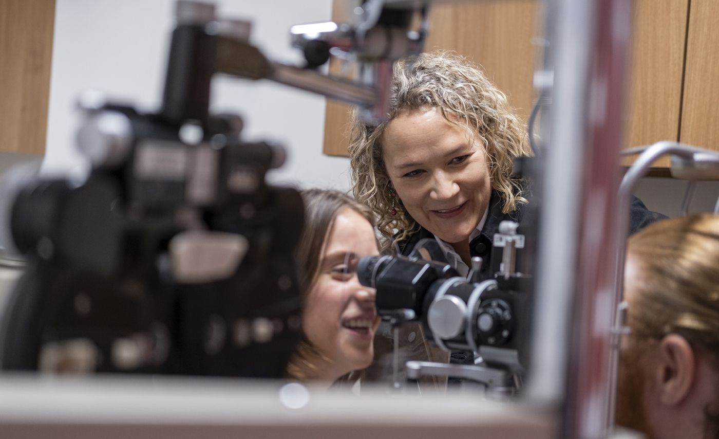 Melissa Bailey observes as students Sarah Olen-Thomas and Ian Binns practice with optometry equipment.