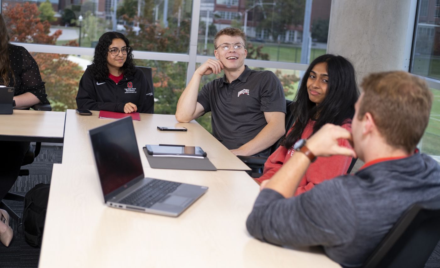 Students sit around a table in discussion.