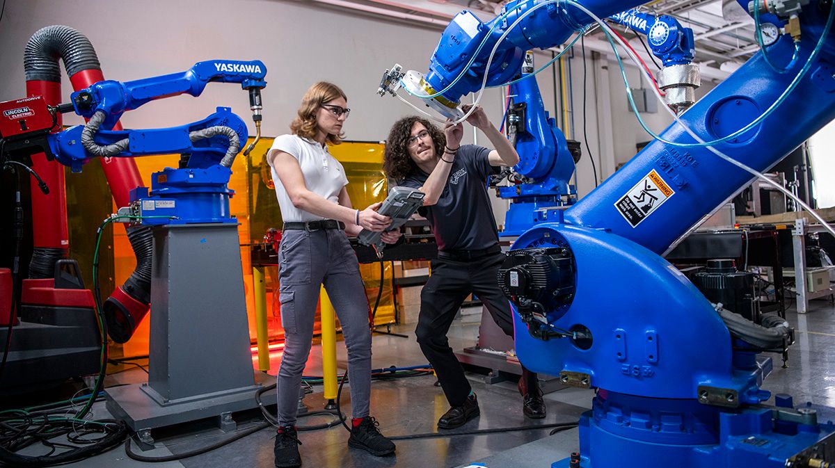 Two researchers work together on a robotic arm.