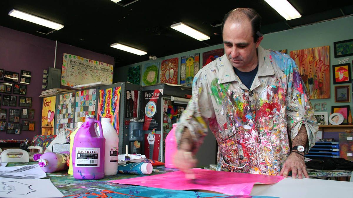 Jeff Sparr paints while dressed in a coach covered with paint splatters.