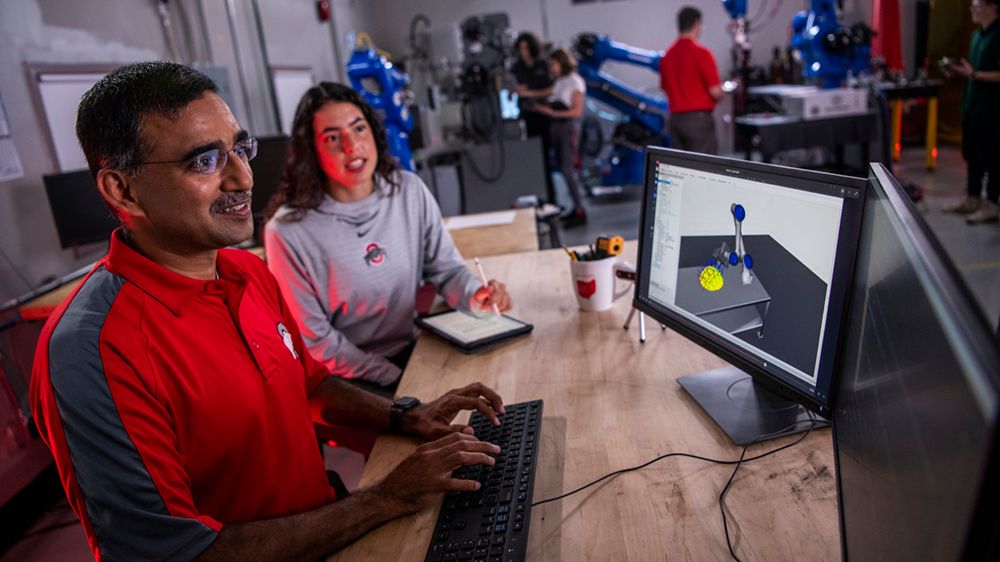 Ohio State researcher Vimal Buck sits next two a student as they both review data.