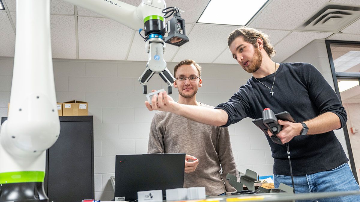 Two students work together on an engineering device