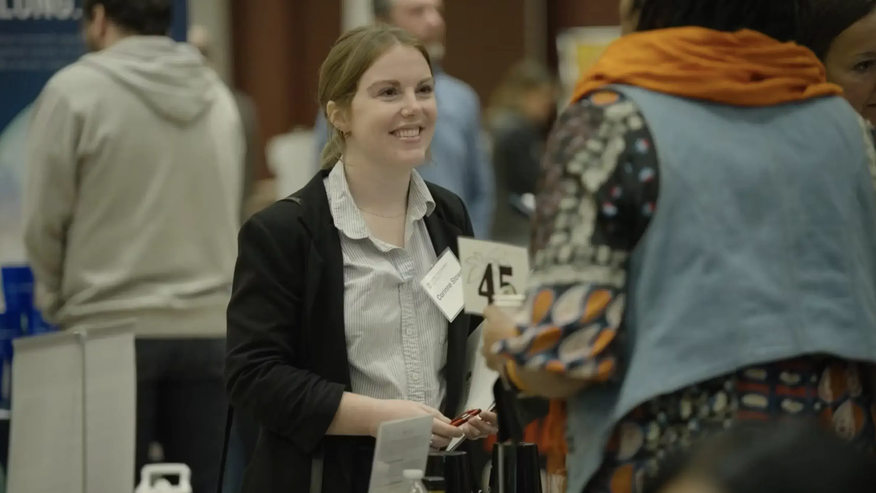 smiling woman greeting another person at a career fair