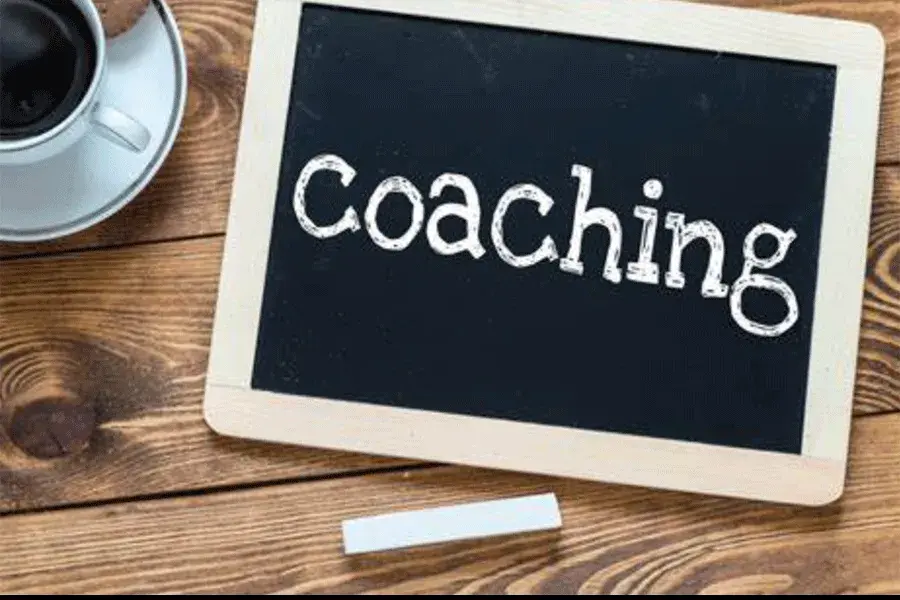 Coaching written on a chalkboard next to a cup of black coffee
